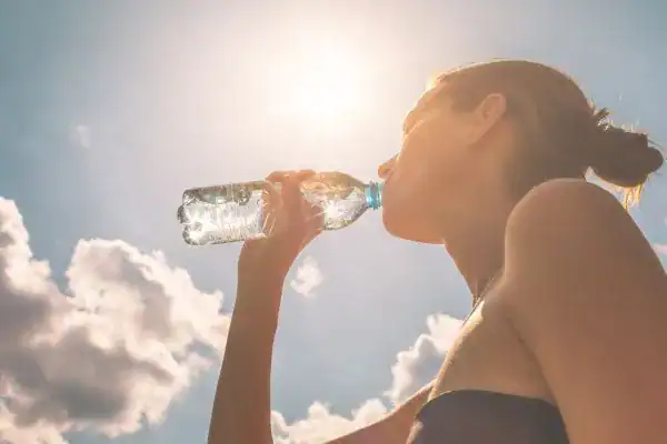 Image of woman drinking water to hydrate Banstead after run.