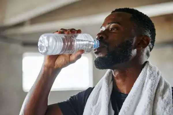 Image of man drinking water to improve hydration Banstead after work out.